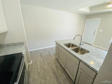 Kitchen with light stone counters, electric stove, and light wood-type flooring