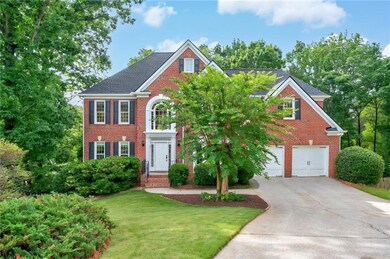 View of front of home, featuring driveway, brick siding, an attached garage, and a front yard