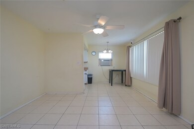 Open tiled living/dining room with open galley kitchen.