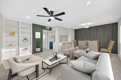 This photo showcases a modern, open-concept living and dining area with sleek furnishings. It features built-in shelves, a ceiling fan, and a stylish accent wall. The space is well-lit and connects seamlessly to a kitchen with a bar counter, creating an inviting atmosphere.