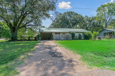 View of front of property featuring driveway, a metal roof, and a carport
