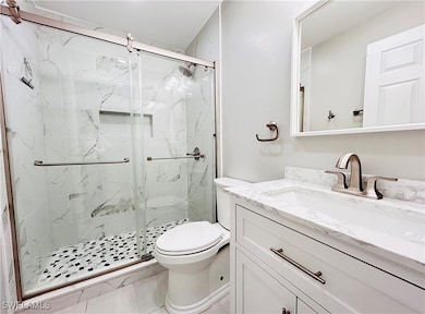 Guest Full bath with toilet, vanity, and a marble