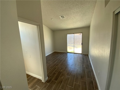 Empty room featuring a textured ceiling, dark wood