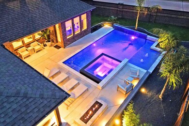 Huge Outdoor Covered Patio with Summer Kitchen overlooks the sparkling Infinity Edge Pool with Hot Tub all Resort Style . Enjoy sitting by the Firepit while listening to the soothing sounds of the water Fountains or relax by the poolside and Smell the Steak on the Grill and enjoy the Impeccable landscaping! Vacation in your own backyard!   