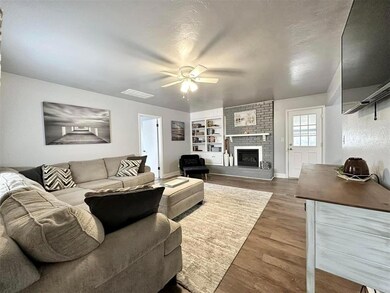 Living room with brick wall, ceiling fan, a firepl