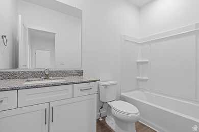 Full bathroom featuring vanity, dark wood-type flooring, and shower / washtub combination