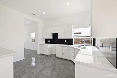 Kitchen with dark marble finish flooring, recessed lighting, decorative backsplash, light stone counters, and white cabinetry
