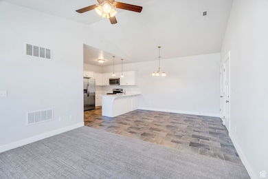 Unfurnished living room with vaulted ceiling, a chandelier, a ceiling fan, and wood finish floors