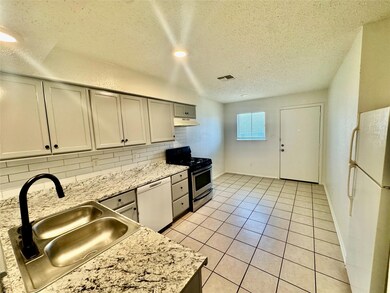 Kitchen with white appliances, a textured ceiling