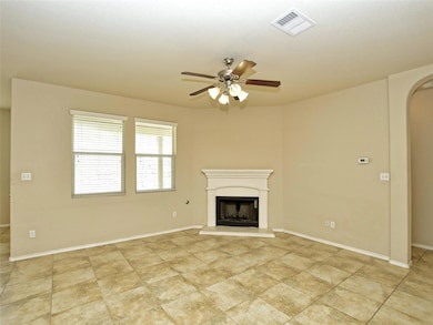 Unfurnished living room featuring arched walkways, a fireplace with raised hearth, and ceiling fan