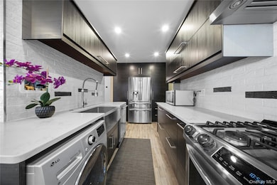 Kitchen featuring stainless steel appliances, light stone countertops, exhaust hood, modern cabinets, and recessed lighting