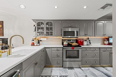 Kitchen featuring gray cabinetry, stainless steel