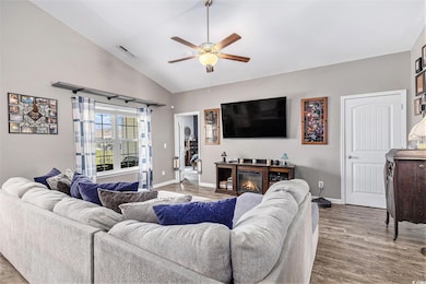 Living area with a ceiling fan, wood finished floors, and high vaulted ceiling