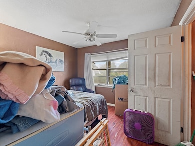 Bedroom with wood-type flooring, a textured ceiling, and ceiling fan