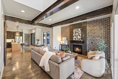 Living room with beam ceiling, a large fireplace, finished concrete flooring, and recessed lighting