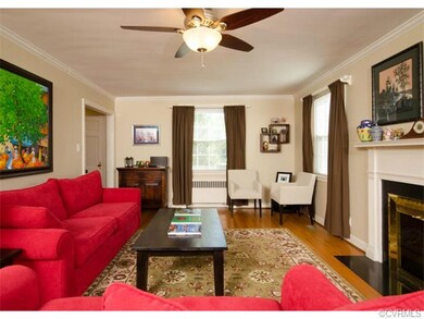 The formal living room has hardwood floors, crown molding, a wood burning fireplace and a ceiling fan with light.