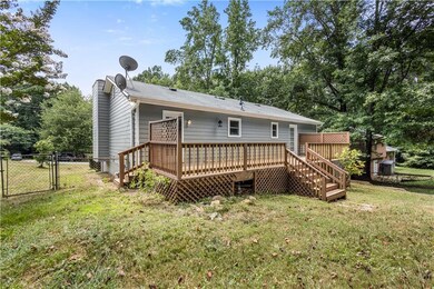 Rear view of property featuring a gate, a deck, and stairs
