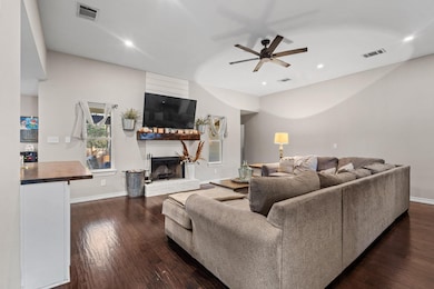 Living area featuring dark wood-style flooring, a fireplace, a ceiling fan, and recessed lighting