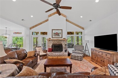 Living room featuring light wood-style floors, high vaulted ceiling, a ceiling fan, a fireplace, and recessed lighting