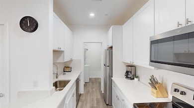 Kitchen featuring white cabinetry, stainless steel