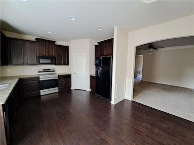 Kitchen with dark wood-type flooring, dark brown c