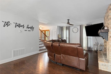 Living area featuring stairway, wood finished floors, a fireplace, and ceiling fan