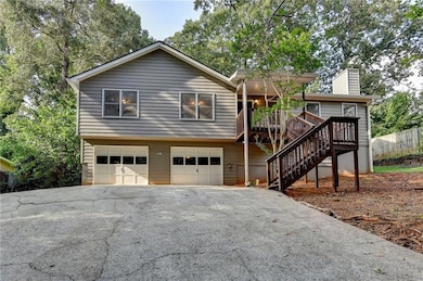 View of front of house with a garage, driveway, a chimney, stairs, and a wooden deck