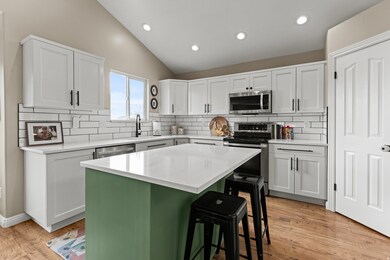 Kitchen with tasteful backsplash, appliances with stainless steel finishes, a center island, lofted ceiling, and a breakfast bar