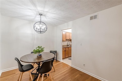 Dining space with a chandelier, light wood-type flooring, and a textured ceiling