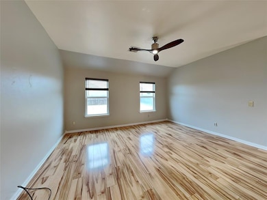 Spare room with light wood-style floors, ceiling fan, baseboards, and lofted ceiling