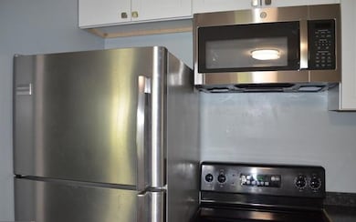 Kitchen with appliances with stainless steel finishes, white cabinets, and dark countertops
