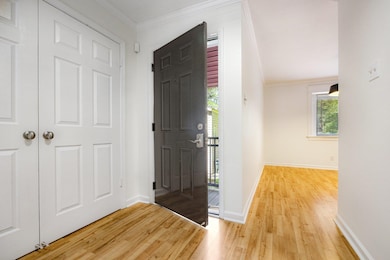 Foyer with light wood finished floors, ornamental molding, and baseboards