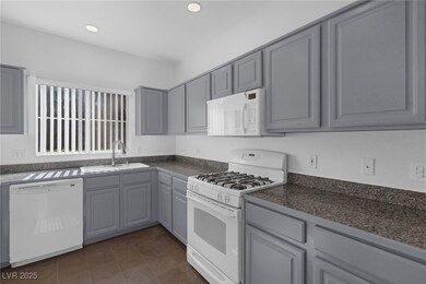 Kitchen with gray cabinets, white appliances, dark countertops, and recessed lighting
