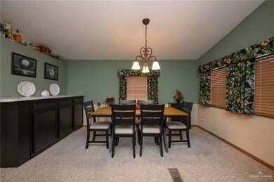 Dining space with a textured ceiling, a notable chandelier, visible vents, and light colored carpet