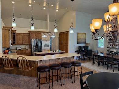 Kitchen featuring a peninsula, decorative light fixtures, a kitchen breakfast bar, white appliances, and brown cabinetry