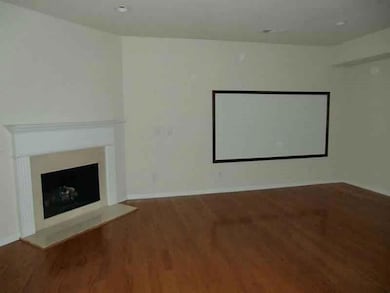 Home theater with dark wood-type flooring and a fireplace with raised hearth