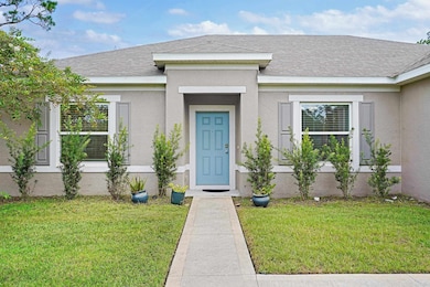 Doorway to property featuring a yard, stucco siding, and a shingled roof