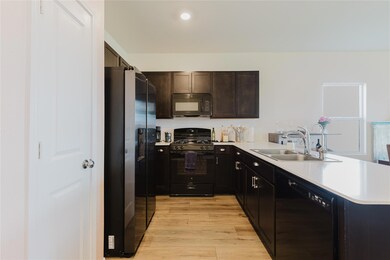Kitchen with black appliances, a peninsula, light