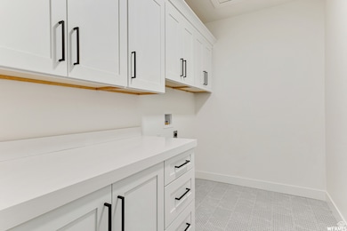 Laundry room with cabinet space, hookup for a washing machine, baseboards, and hookup for an electric dryer