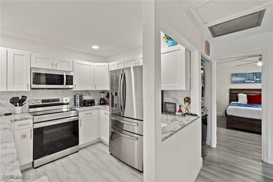 Kitchen featuring white cabinetry, light stone cou
