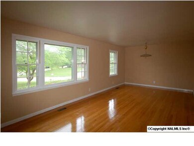 Large living room with dining area has beautiful wood floors and picture window for natural light.