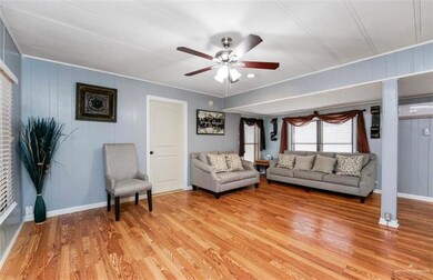Living room with ornamental molding, light wood-type flooring, and ceiling fan