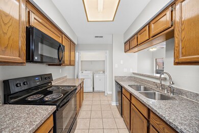 This kitchen features granite countertops, wooden cabinets, and modern appliances, with a convenient laundry area nearby.