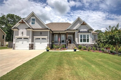 Craftsman-style house featuring board and batten siding, covered porch, concrete driveway, a front yard, and stone siding