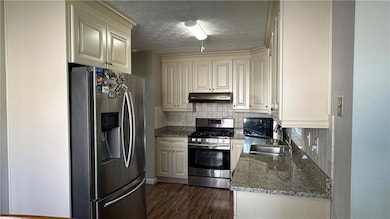 Kitchen with dark wood-style floors, backsplash, u