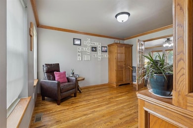 Living area featuring light wood finished floors and crown molding