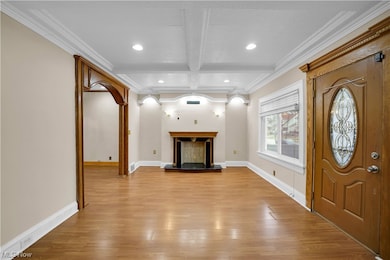 Entrance foyer with crown molding, coffered ceiling, light hardwood / wood-style flooring, and beam ceiling