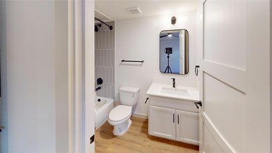 Full bath featuring visible vents, toilet, wood fi