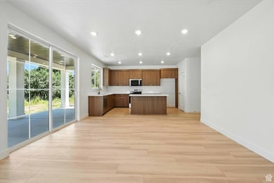 Kitchen featuring recessed lighting, a center island, light countertops, stainless steel appliances, and light wood-style flooring