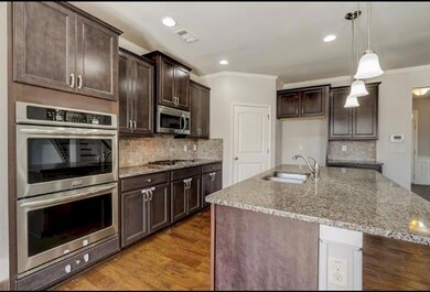 Kitchen with crown molding, appliances with stainless steel finishes, a sink, and visible vents